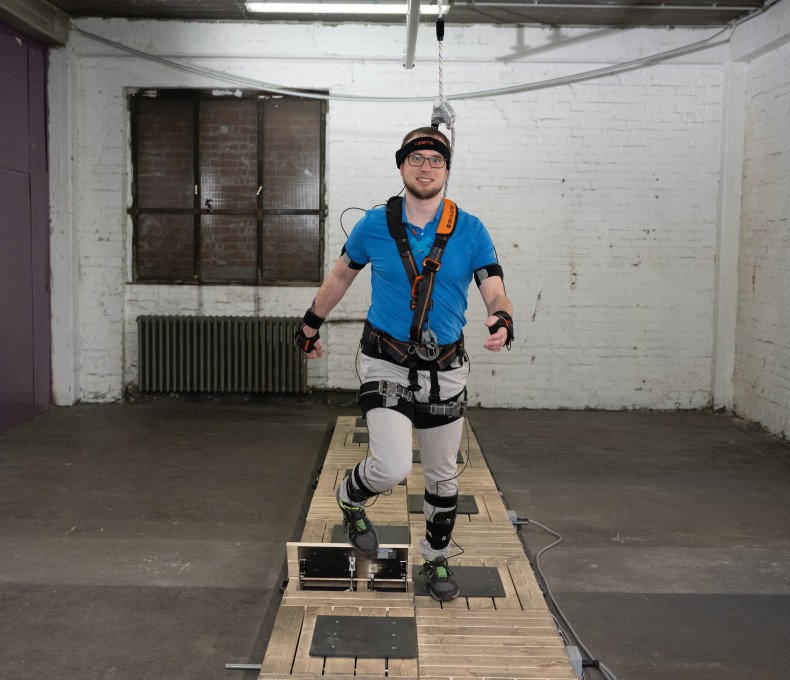 Zu sehen ist eine Testperson in einem Ganzkörpermessanzug auf einem Laufband. Zu sehen ist eine Testperson in einem Ganzkörpermessanzug auf einem Laufband.