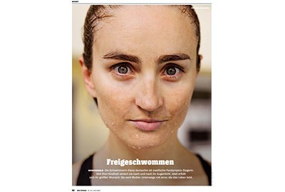 Gesicht einer jungen Schwimmerin, zufriedener Blick, Haare nach hinten gekämmt, Wasser perlt von ihrer Haut. Text unten: Freigeschwommen.